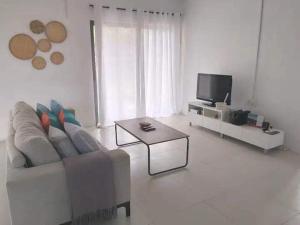 sala de estar blanca con sofá y TV en Le Kato Lux Rodrigues, en Rodrigues Island