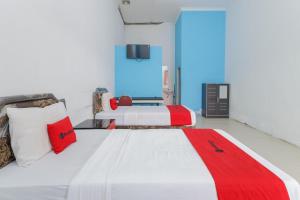a bedroom with two beds with red and white pillows at RedDoorz at Bypass Town Square Mojokerto in Mojokerto