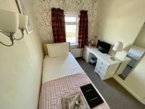 um pequeno quarto com uma cama e uma secretária com uma televisão em Windsor Park promenade em Blackpool