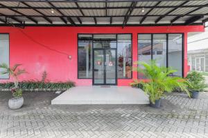 a red building with plants in front of it at RedDoorz at Bypass Town Square Mojokerto in Mojokerto