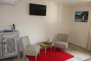 a living room with two chairs and a table and a tv at LE RUBINJO 2 in Saint-Benoît