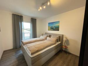 ein Schlafzimmer mit einem Bett in einem Zimmer mit einem Fenster in der Unterkunft Luxuriöse Wohnung Zentral mit großem Balkon in Losheim