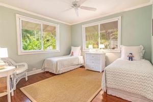 a bedroom with two beds and a chair and windows at Beautiful and Cheerful Hale Mokolea in Lanikai in Kailua