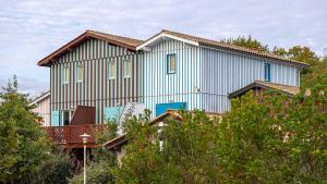 una grande casa blu con balcone e alberi di Madame Vacances Les Rives Marines a Le Teich