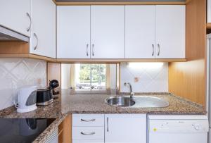 a kitchen with white cabinets and a sink at LongLands Peak at Windmill Hill in Albufeira