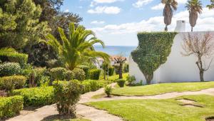 a garden with bushes and trees and the ocean at LongLands Peak at Windmill Hill in Albufeira