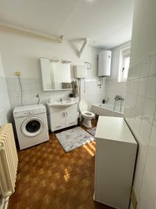 een witte badkamer met een wastafel en een wasmachine bij Apartman MS in Bosanska Dubica