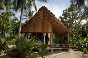 uma pequena cabana com um banco em frente a algumas palmeiras em Metita Beach & Dive Resort em Doruba