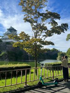 eine Person, die ein Bild von einem Schloss mit einem Roller macht in der Unterkunft Sakura Garden Hotel in Osaka