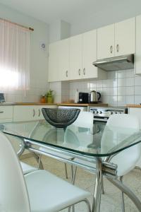 Strovolos的住宿－ALEX APARTMENT，厨房配有玻璃桌和白色椅子