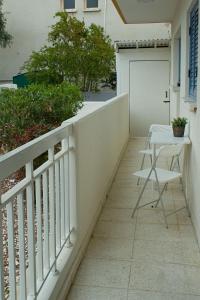 Strovolos的住宿－ALEX APARTMENT，阳台配有白色栏杆和桌椅。