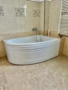 a white tub in a bathroom with a tile floor at Casa Rus in Leordina