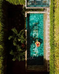 einen Blick über den Pool mit einer Person im Wasser in der Unterkunft Canggu Hype in Canggu