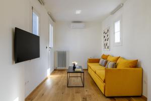 een woonkamer met een gele bank en een flatscreen-tv bij Your 4 bdrm Dream House Acropolis View & Jacuzzi in Athene