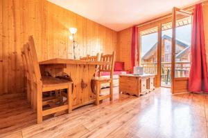 um quarto em madeira com uma secretária, uma cama e uma janela em Madame Vacances Les Chalets Du Berger em La Feclaz