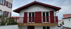 a house with red doors and a balcony at Biarritz appartement 2 adultes, 2 enfants à proximité immédiate des plages et des commerces in Biarritz