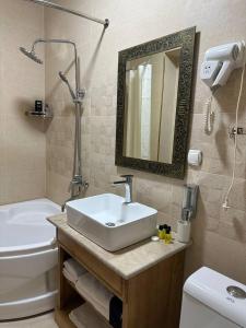 As-Salam Boutique Hotel في بوكسورو: حمام مع حوض ومرحاض ومرآة