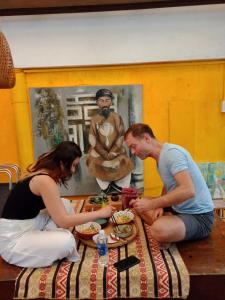mężczyzna i kobieta siedzący przy stole jedzący jedzenie w obiekcie Le Home w mieście Hue