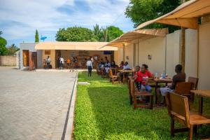 een groep mensen die aan tafels op het gras zitten bij Inkaba Resort & Conference Centre Kilifi in Kilifi