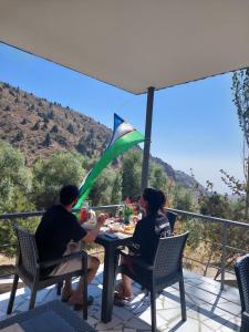two people sitting at a table under an umbrella at Eagle Rock Nature Lodge in Angren