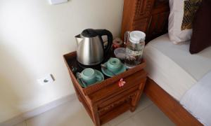 a tray with a coffee maker and cups on a bed at Danasari Homestay in Ubud