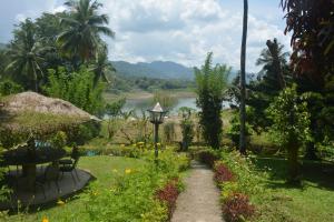 een tuin met een tafel en stoelen en een meer bij Oruthota Chalets in Kandy
