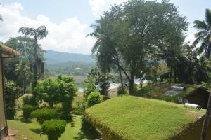 uitzicht op een tuin met bomen en een rivier bij Oruthota Chalets in Kandy
