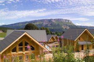 a row of wooden houses with a mountain in the background at Madame Vacances Les Chalets Du Berger in La Féclaz