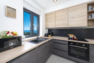 kuchnia z czarnymi i drewnianymi szafkami oraz oknem w obiekcie Apartment Skyline w mieście Cavtat