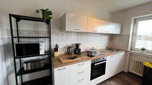 uma cozinha com armários brancos e um frigorífico preto em Work & Stay Apartments in Bad Laer em Bad Laer