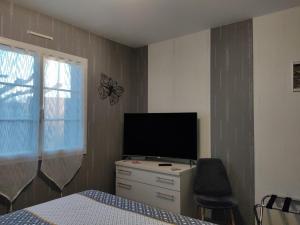 - une chambre avec un lit et une télévision sur une commode dans l'établissement A la bonne étape, à Sassenay