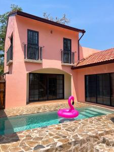 uma casa cor-de-rosa com um pato de borracha cor-de-rosa numa piscina em Pink Villa by Tubtao Sleepy Hill em Pong Talong