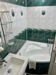 La salle de bains est pourvue d'une baignoire blanche et d'un lavabo. dans l'établissement Pensiunea Eden, à Sinaia