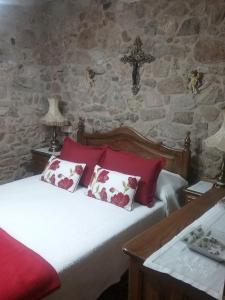 una camera da letto con un letto con cuscini rossi e una croce di Casa Do Conde a Caldas de Reis