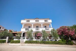 a white building with pink flowers in front of it at Apartments Marina in Petrcane