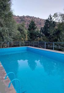 a blue swimming pool with a mountain in the background at Eagle Rock Nature Lodge in Angren