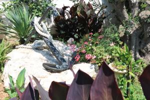 a garden with a statue on a rock with flowers at Apartments Marina in Petrcane