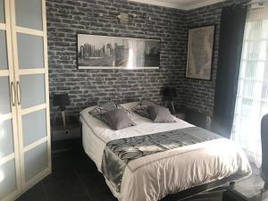 Ce lit se trouve dans une chambre dotée d'un mur en briques. dans l'établissement Chambres chez l'habitant Villa l'Île aux Anges, à Saint-André