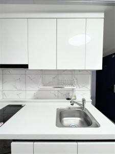 a kitchen with white cabinets and a sink at W Premium Guesthouse Incheon airport in Incheon