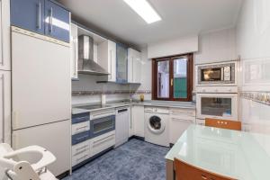 cocina con armarios blancos, lavadora y secadora en Portu Cozy by Aston Rentals, en Portugalete