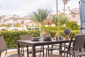 a table and chairs on a patio with palm trees at Es descans in Can Picafort