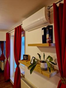a room with red curtains and a plant on a shelf at Slnečný byt v blízkosti historického centra Free Parking in Trenčín