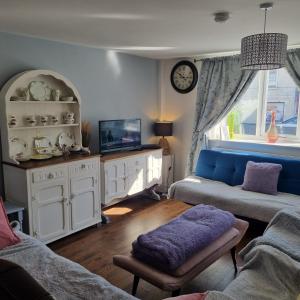 a living room with a couch and a tv at Dare Valley Cottage Ex miners cottage Near Zip World Pen y fan Waterfalls in Aberdare