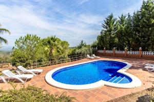 a swimming pool in a yard with chairs and a fence at Catalunya Casas Elegant Mountain Villa just 30km to Barcelona in Corbera de Llobregat