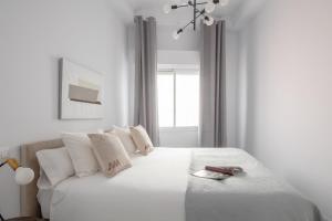 - une chambre blanche avec un lit blanc et des oreillers blancs dans l'établissement Suites Maestranza - Puerta del Arenal by Magno Apartments, à Séville