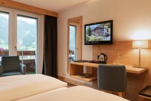 a hotel room with a bed and a desk and a television at Hotel Restaurant Alpina in Grindelwald