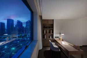 Habitación con escritorio y ventana con vistas a la ciudad. en Genpla Hotel, Shenzhen Qianhai en Shenzhen