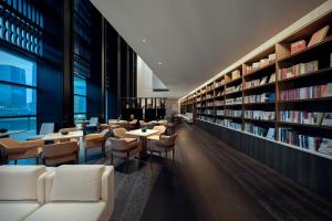 een bibliotheek met witte stoelen, tafels en boekenplanken bij Genpla Hotel, Shenzhen Qianhai in Shenzhen