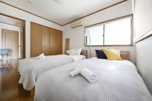 a bedroom with three beds with white sheets and a window at Pirane House 201 東京スカイツリー浅草 押上駅が徒歩圏内 無料wifi in Tokyo