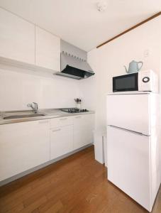 a white kitchen with a sink and a microwave at Pirane House 201 東京スカイツリー浅草 押上駅が徒歩圏内 無料wifi in Tokyo